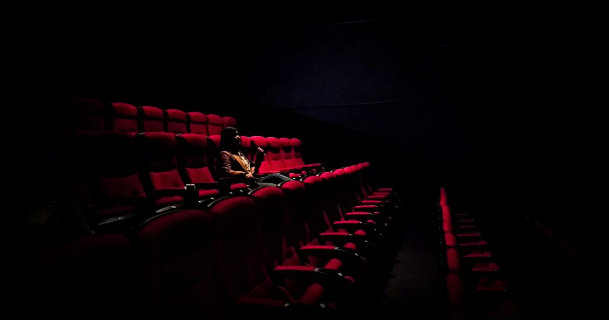 Photo of a woman sitting alone in a theater by Karen Zhao